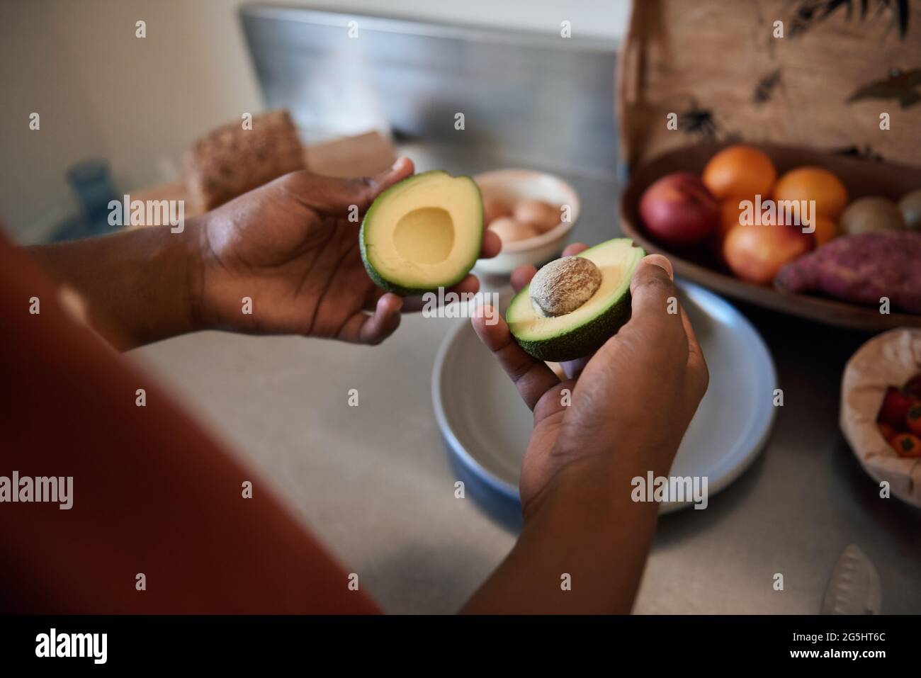 Afrikanischer Mann schneidet in seiner Küche eine Avocado in die Hälfte Stockfoto