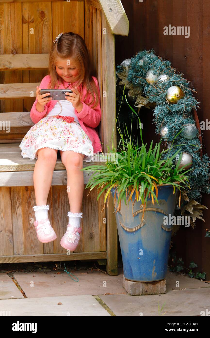 Ein 5-jähriges Mädchen, das Videos auf einem Mobiltelefon ansieht Stockfoto