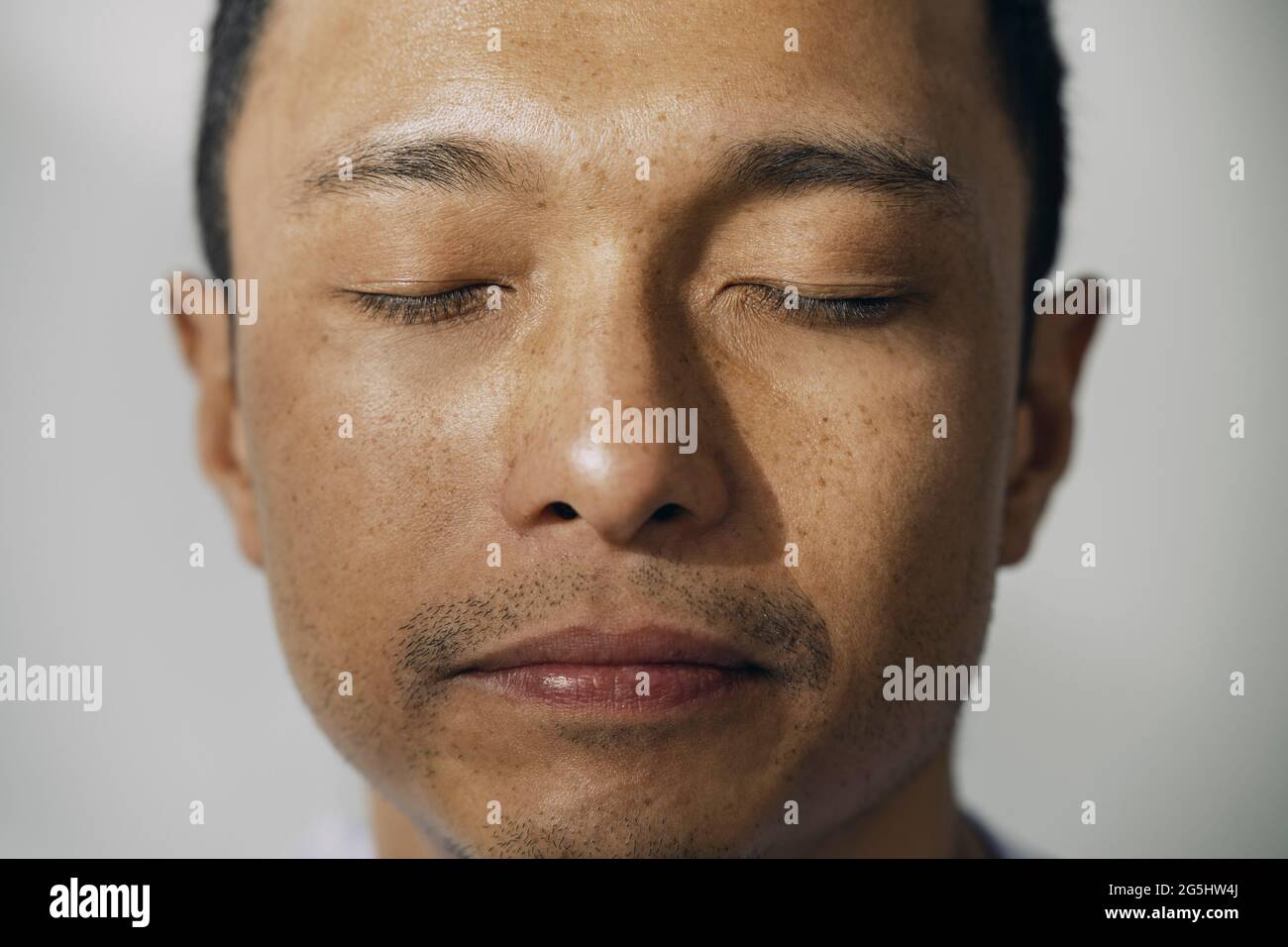 Mittelerwachsener Mann Augen geschlossen gegen weiße Wand Stockfoto Mittelerwachsener Mann Augen geschlossen gegen weiße Wand Stockfoto