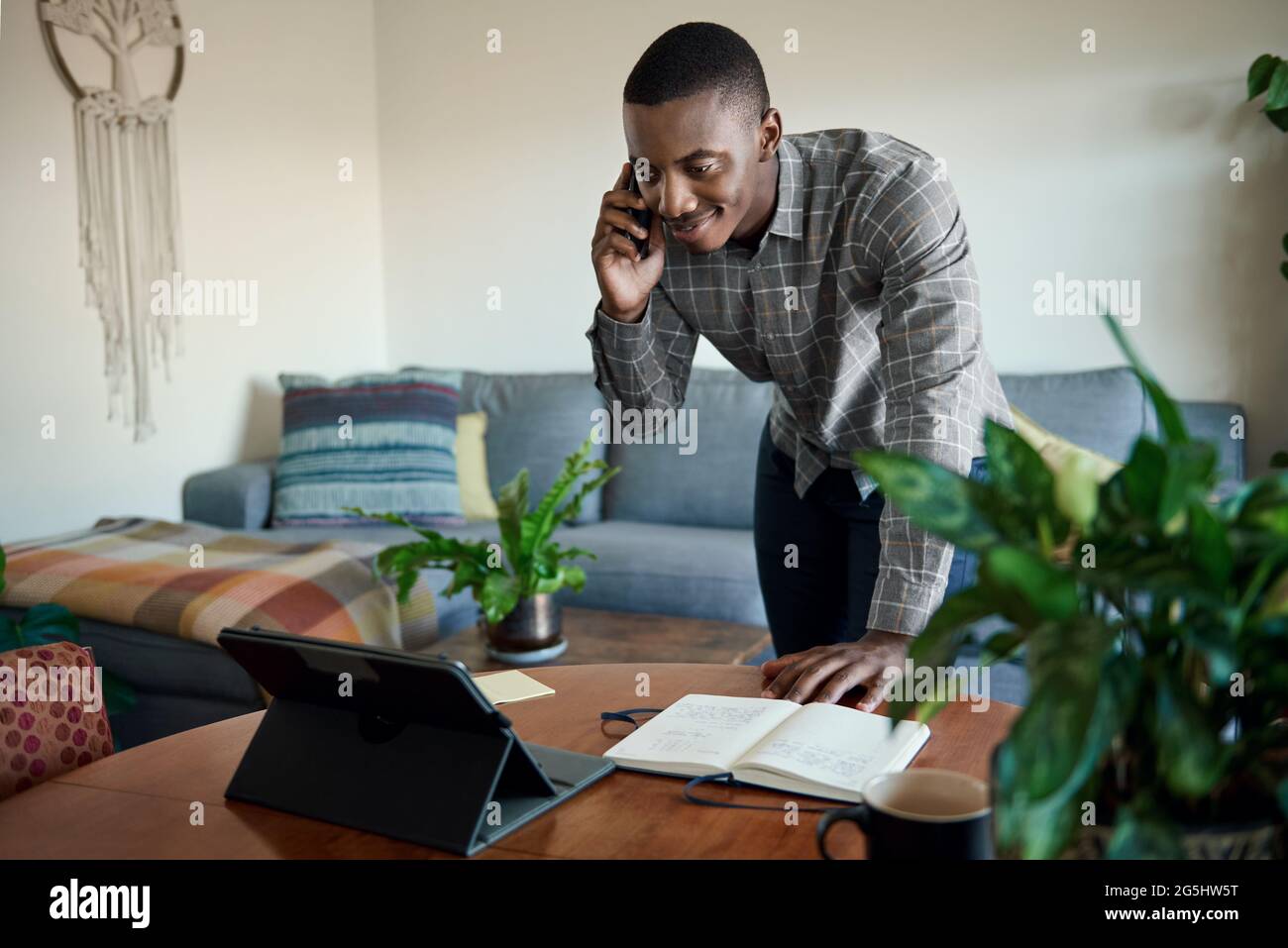 Afrikanischer Geschäftsmann, der von zu Hause aus mit seinem Handy und Tablet arbeitet Stockfoto
