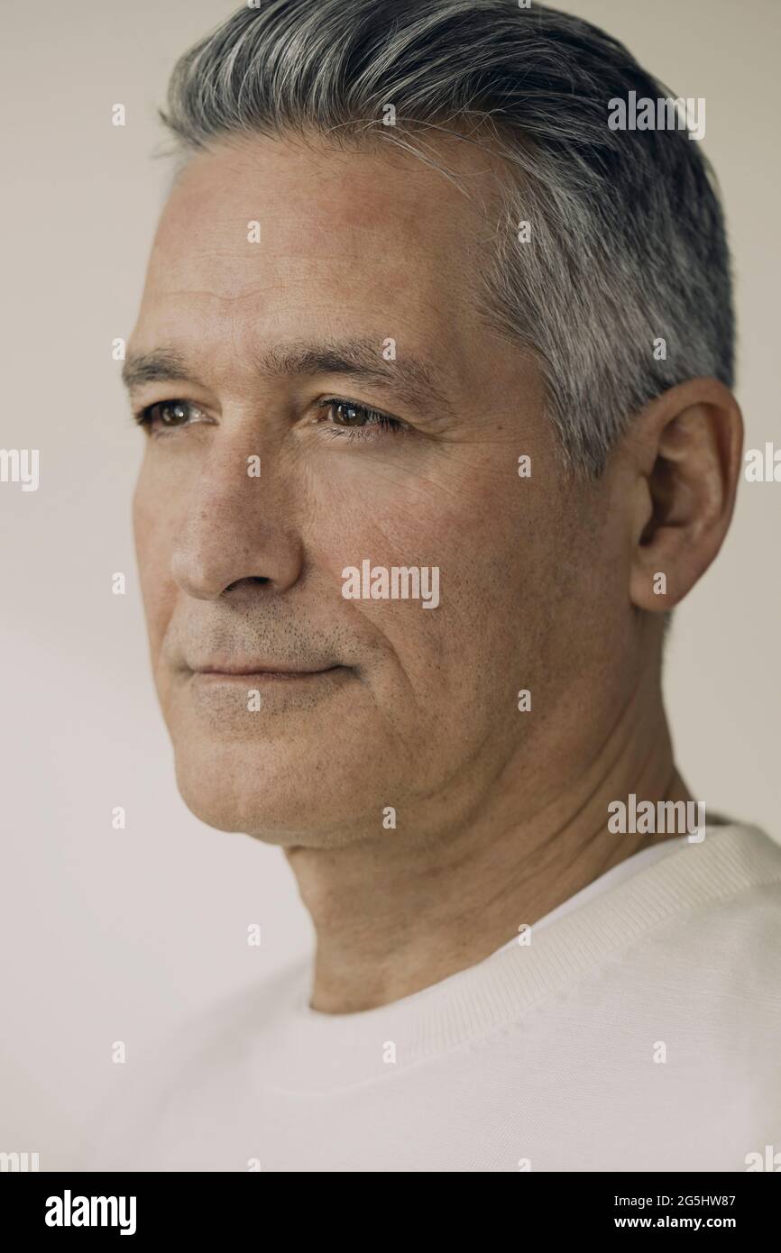 Reifer Mann mit grauen Haaren vor beigem Hintergrund Stockfoto