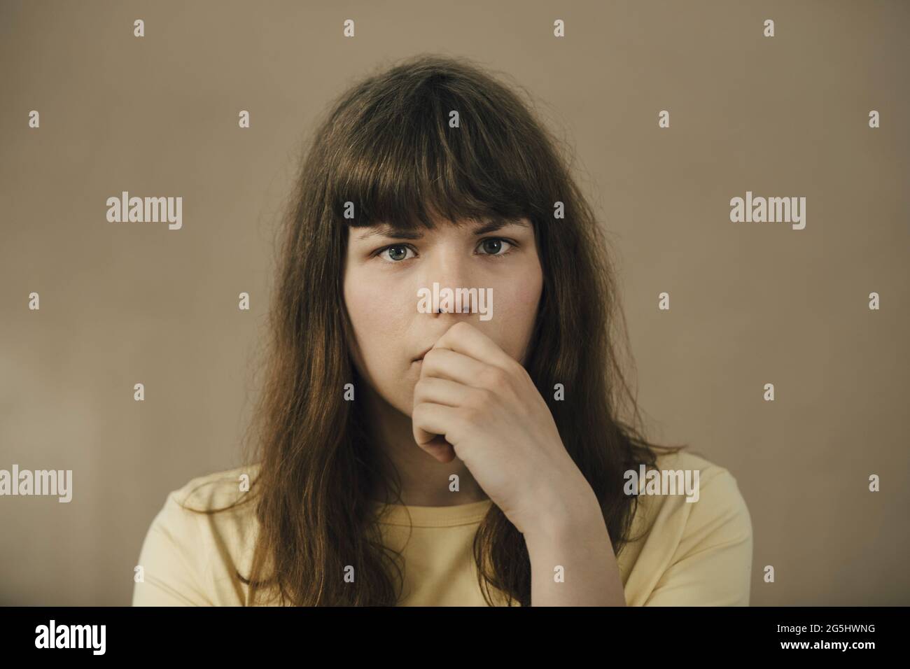 Porträt einer verwirrten jungen Frau vor beigem Hintergrund Stockfoto