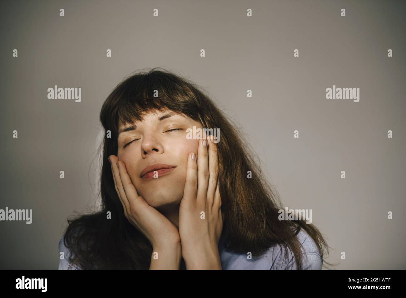 Junge Frau mit geschlossenen Augen vor weißem Hintergrund Stockfoto
