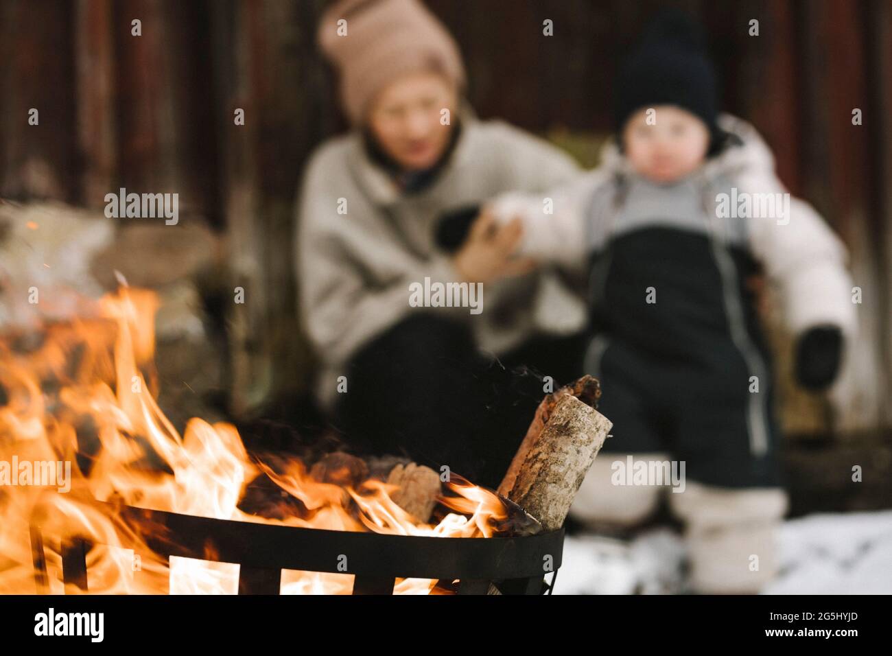 Brennendes Holz in der Feuerstelle gegen Frau und Tochter im Winter Stockfoto