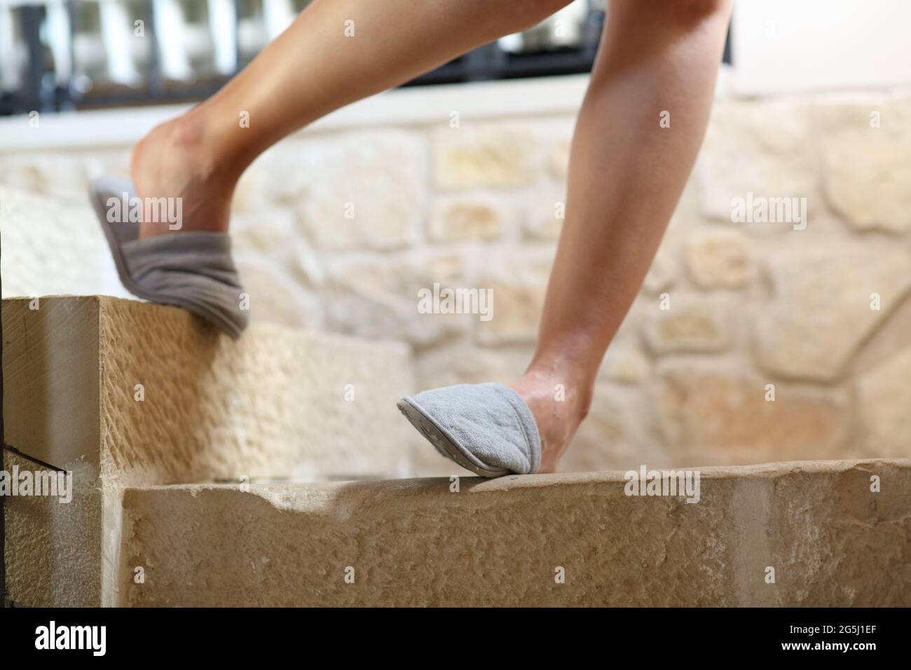 Nahaufnahme einer Frau, die die Beine stolpert und den Knöchel verstaucht, wenn sie die Treppe hinuntergeht Stockfoto