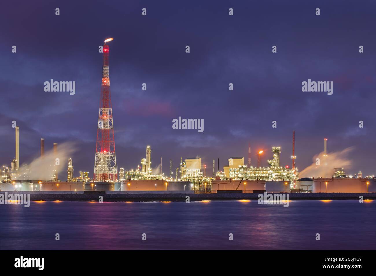 Nachtszene mit beleuchteter petrochemischer Produktionsanlage am Flussufer, Hafen von Antwerpen Stockfoto