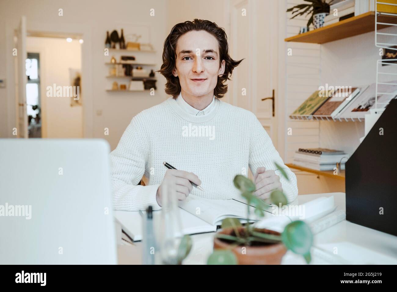 Porträt eines lächelnden männlichen professionellen Sitzers am Schreibtisch im Heimbüro Stockfoto