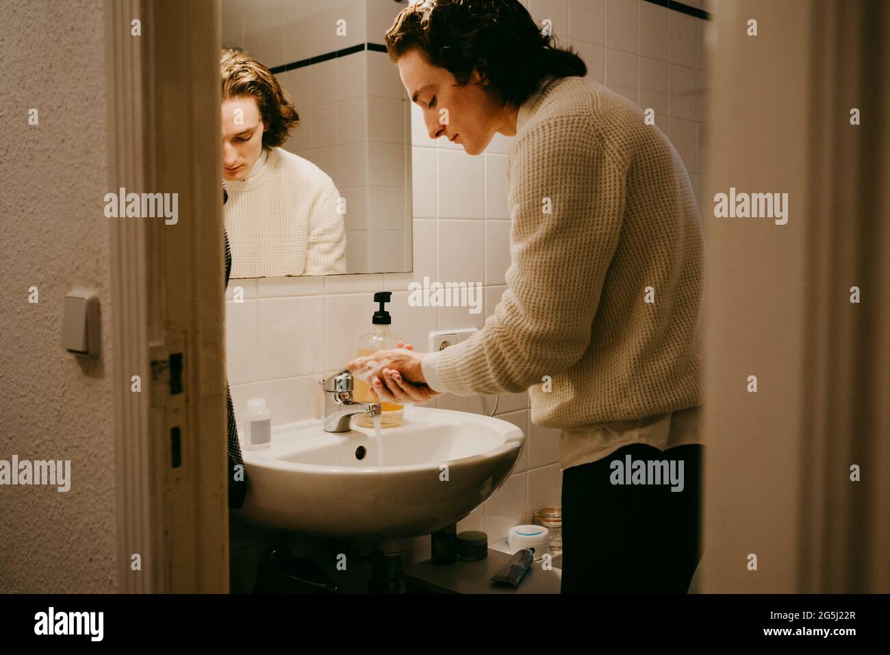 Mann mit mittlerem Erwachsenenalter, der sich im Badezimmer zu Hause die Hände wäscht Stockfoto