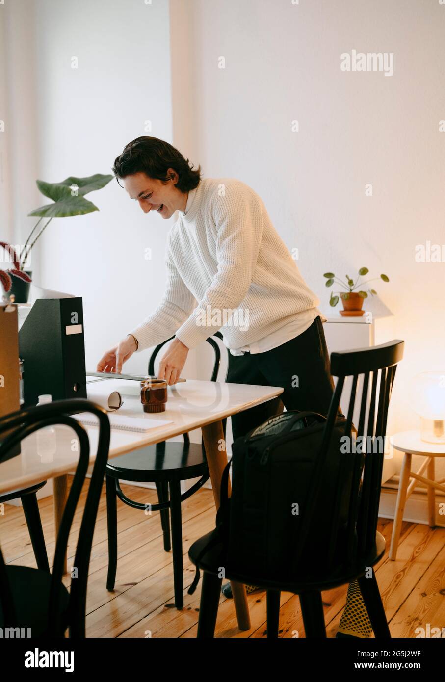 Fröhlicher Geschäftsmann, der im Heimbüro am Schreibtisch steht Stockfoto