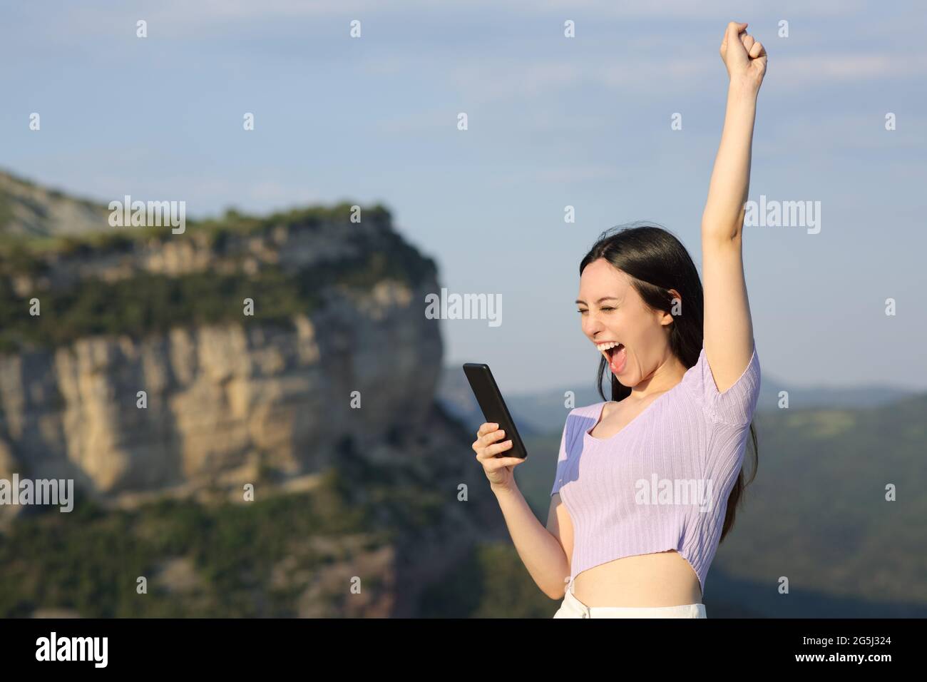 Aufgeregt asiatische Frau Überprüfung Smartphone in den Bergen im Urlaub Stockfoto