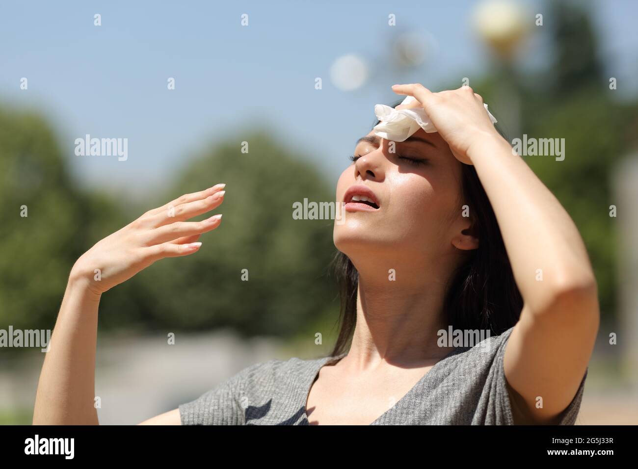 Gestresste asiatische Frau trocknet Schweiß mit einem Tuch an einem warmen Sommertag Stockfoto