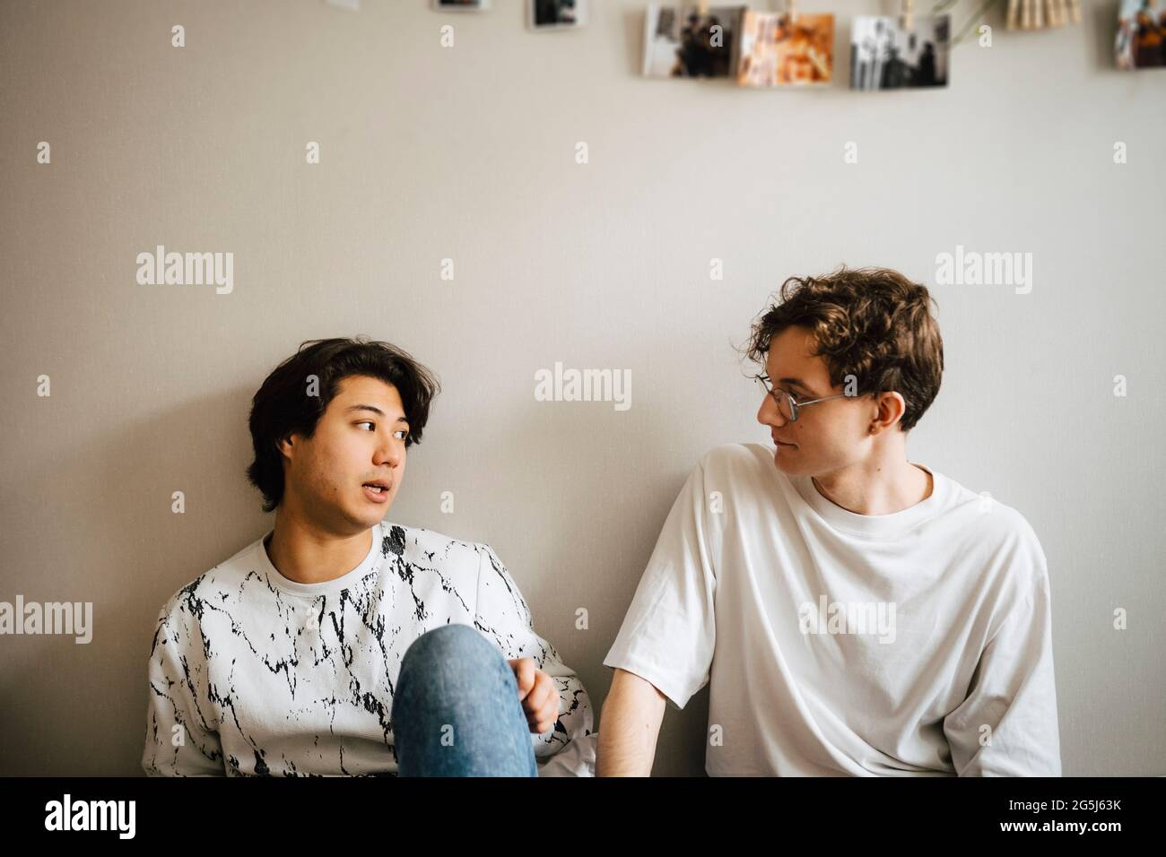 Männliche Freunde reden, während sie zu Hause im Schlafzimmer sitzen Stockfoto