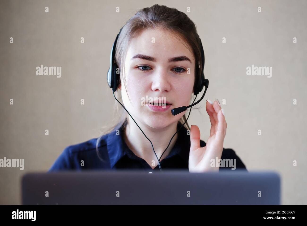 Junge Callcenter-Mitarbeiterin, die mit einem Kunden in einem Headset spricht - Telemarketing-Mitarbeiter in einem Büro mit Laptop gibt Kunden Ratschläge - Co Stockfoto