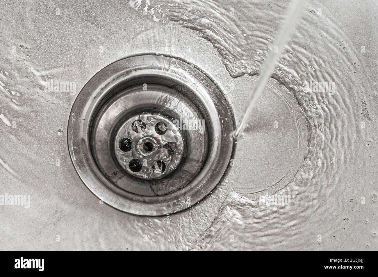 Wasser fließt in den Abfluss des Küchenwaschbecken aus Edelstahl Stockfoto