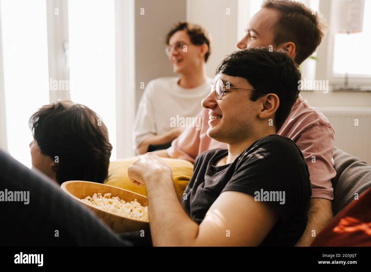 Multiethnische männliche Freunde, die Popcorn essen, während sie im Wohnzimmer Sport treiben Stockfoto