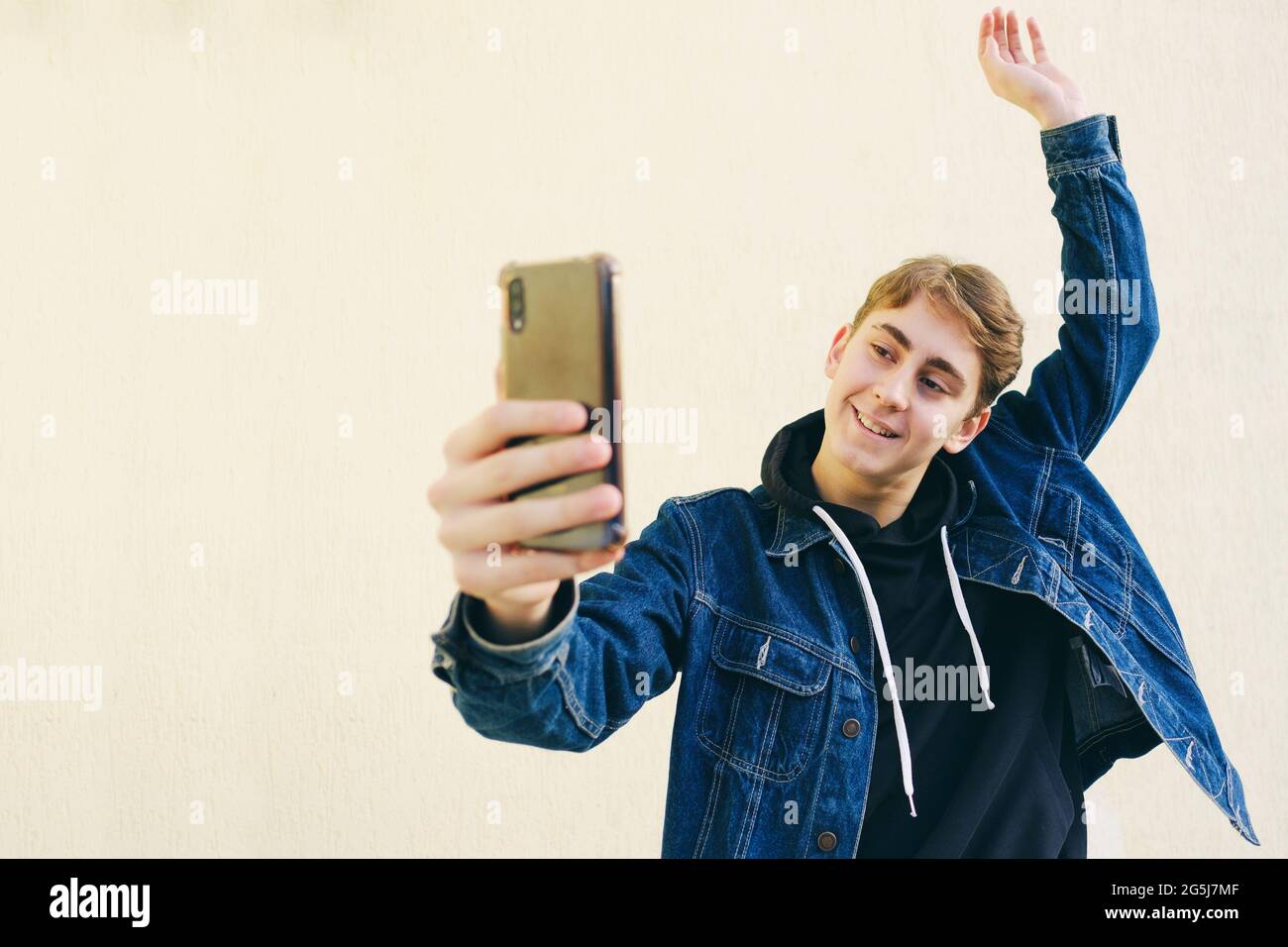 Ein Teenager macht ein Selfie - ein junger Mann macht ein Foto von sich selbst auf einem Smartphone - ein glücklicher Teenager macht ein Foto von sich selbst auf seinem Handy gemacht a h Stockfoto