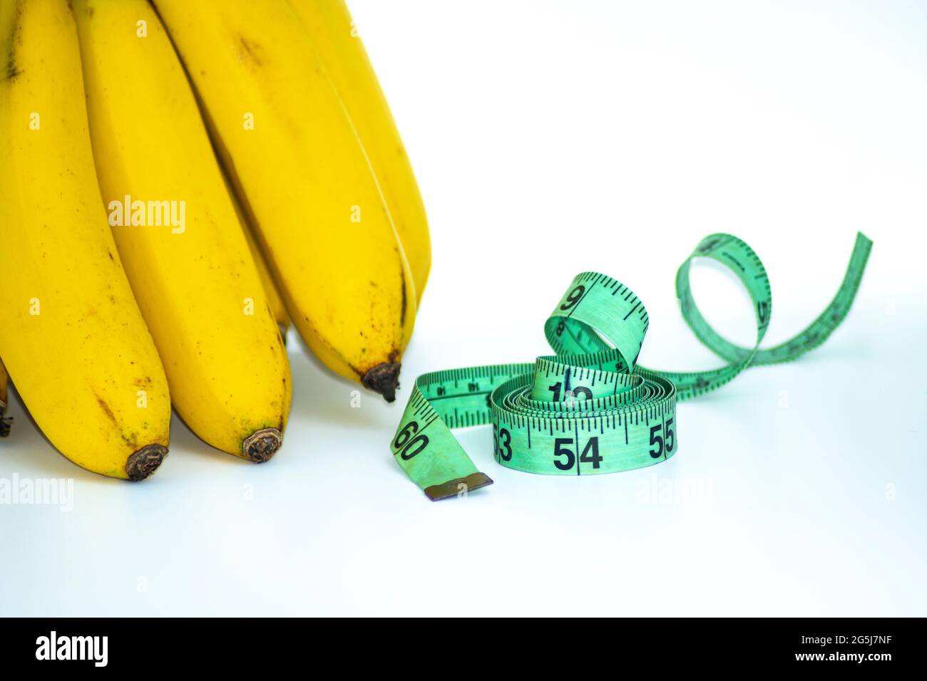 Bund Banane mit Maßband isoliert auf weiß - Diät-Konzept Stockfoto