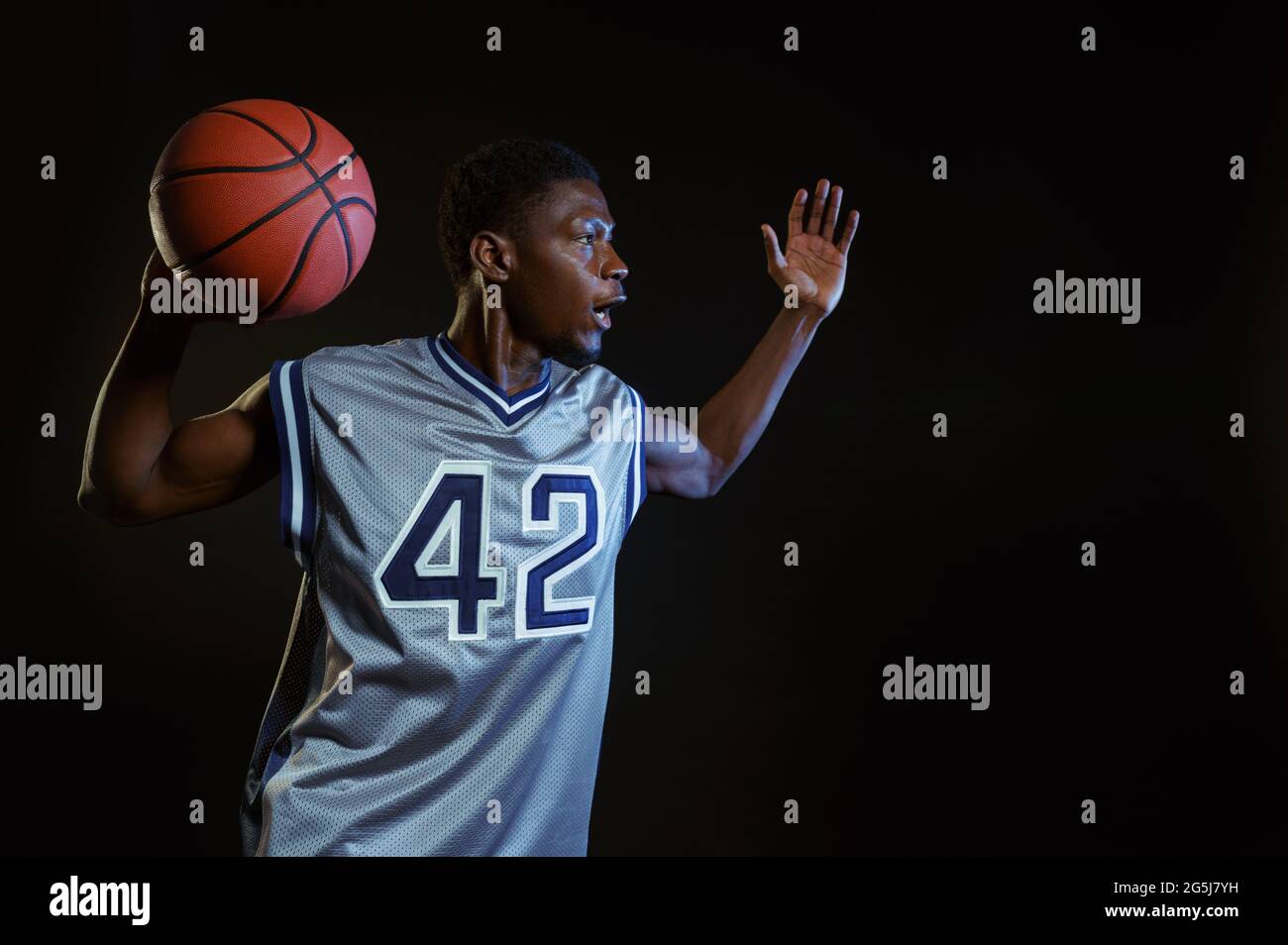 Aggressiver Basketballspieler posiert mit Ball Stockfoto