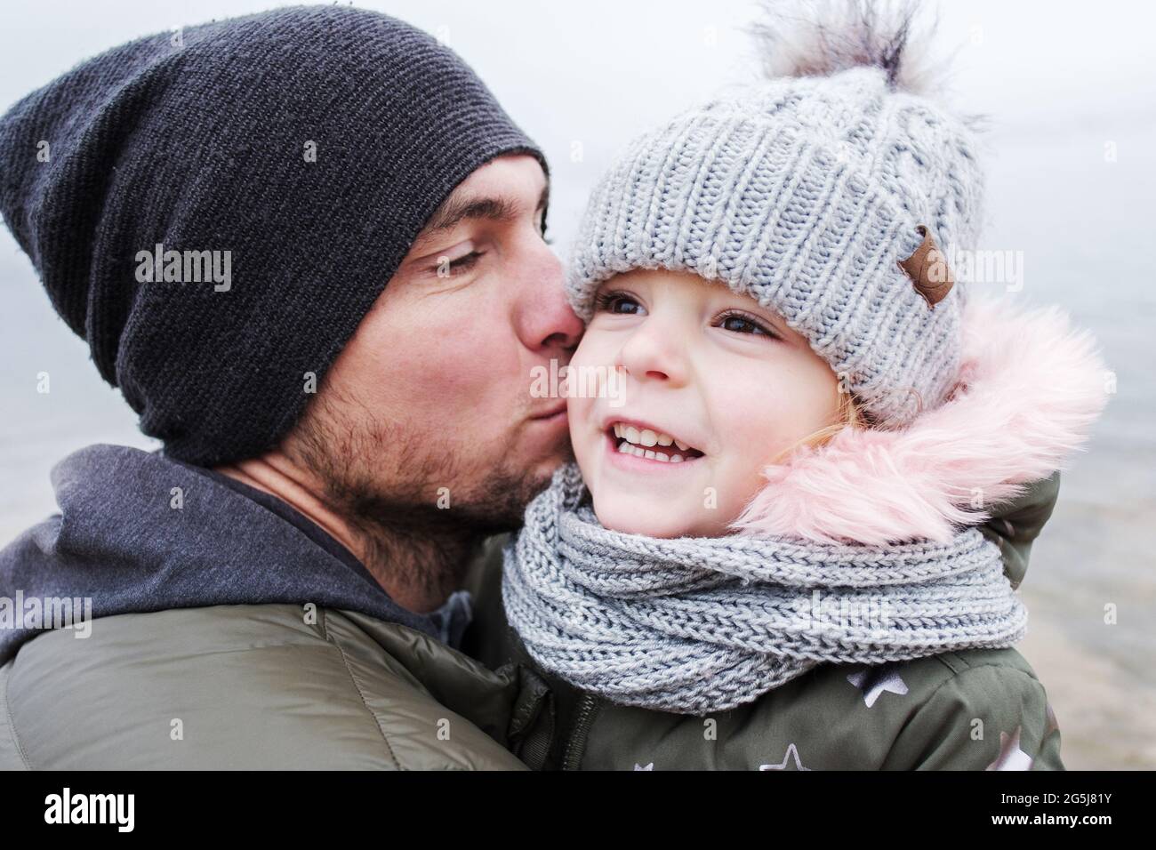 Vater küsst seine kleine Tochter und sie freuen sich über ihre Beziehung - Vater und Tochter haben Spaß zusammen - Single Papa kümmert sich um seine kleine da Stockfoto