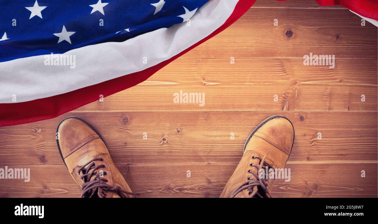 Zusammensetzung der Füße in Arbeitsstiefeln und amerikanischer Flagge, auf Holzboden Stockfoto