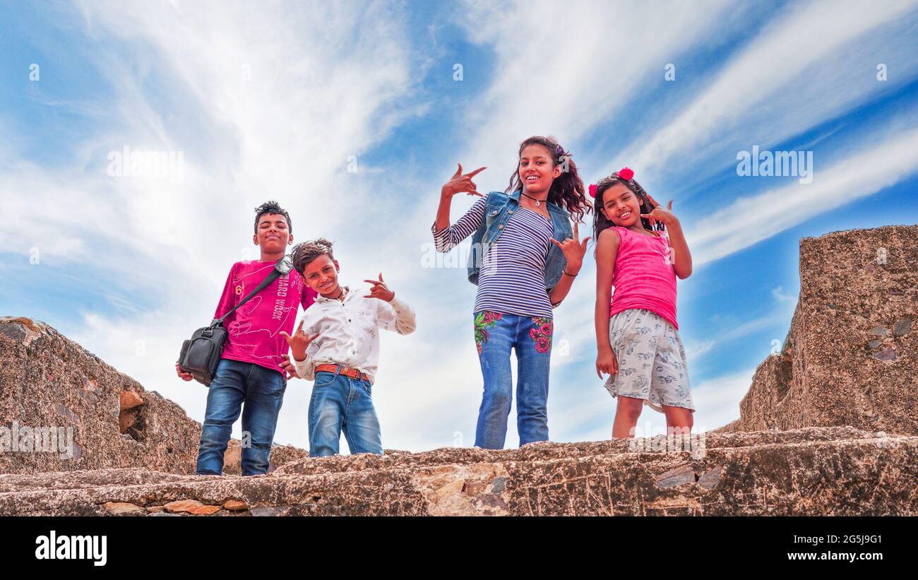 Vier Schulfreunde genießen auf einer Reise-Sehenswürdigkeit und Spaß miteinander machen. Frontansicht von aufgeregten fröhlichen Schulkindern mit weißen Wolken Hintergrund. Stockfoto