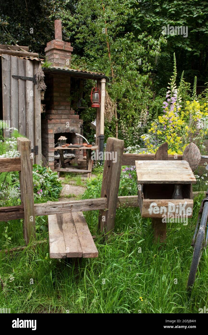 The Fenland Alchemist Garden' mit einem Stil durch einen Holzzaun, wilden  Blumen und einem Backsteinofen und Kamin, rustikalem Briefkasten  Stockfotografie - Alamy