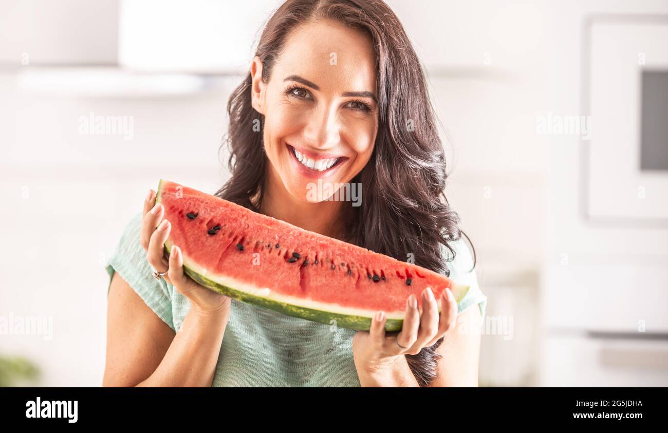 Frau hält ein großes Stück Wassermelone und lächelt. Stockfoto