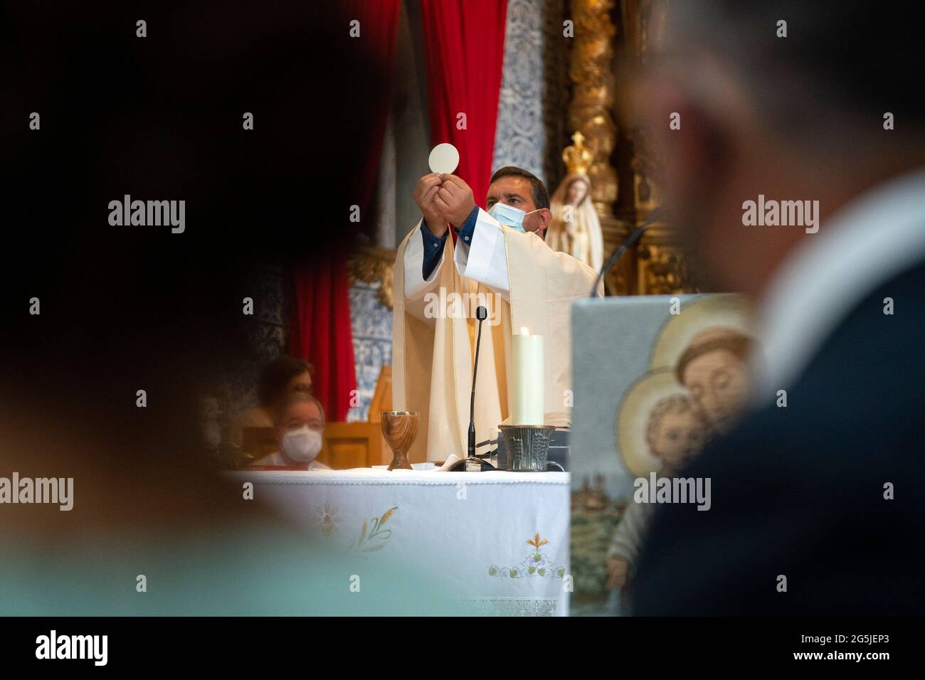 Katholischer Priester mit Gesichtsmaske bei der Feier der Messe während der Pandemie COVID-19 Stockfoto