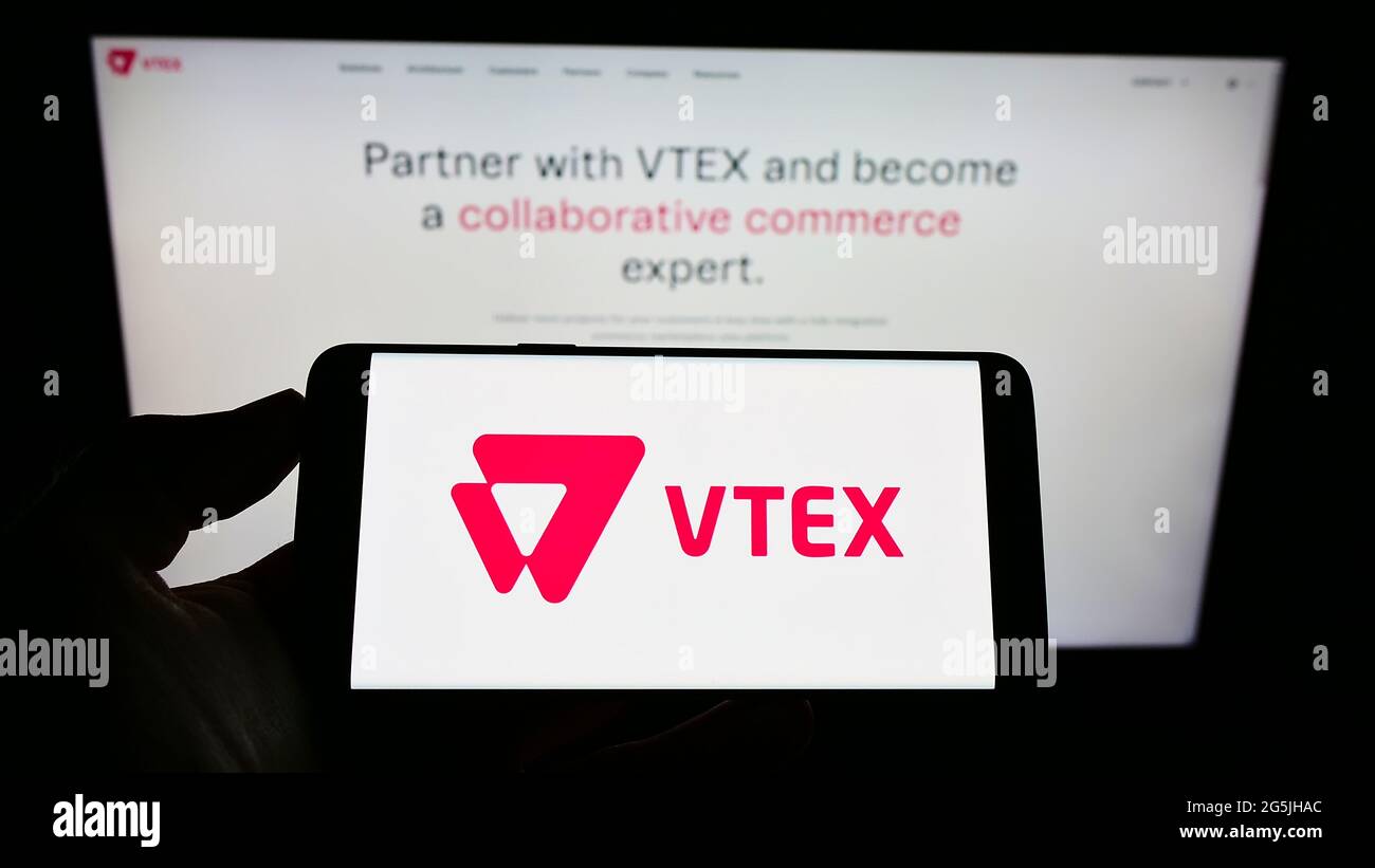 Person, die das Smartphone mit dem Logo der Firma VTEX Commerce Cloud Solutions LLC auf dem Bildschirm vor der Website hält. Konzentrieren Sie sich auf die Telefonanzeige. Stockfoto