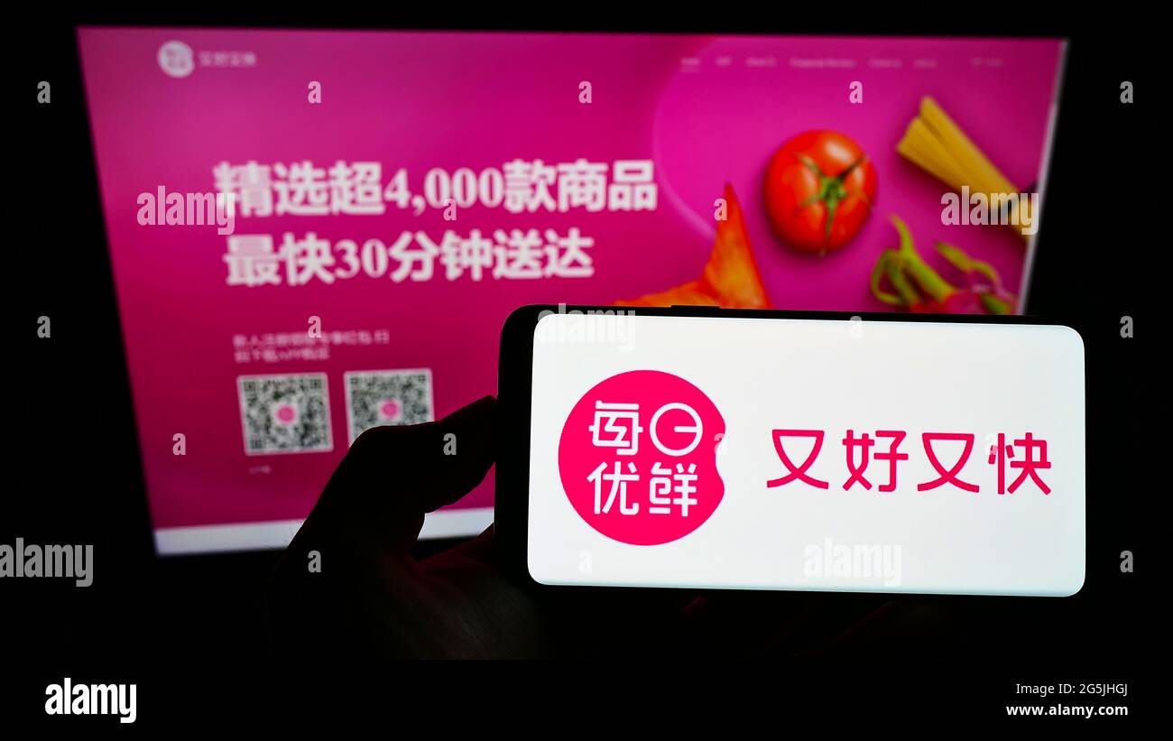 Person, die Smartphone mit dem Logo der chinesischen Firma Beijing Missfresh E-Commerce Co. Ltd. Auf dem Bildschirm vor der Website hält. Konzentrieren Sie sich auf die Telefonanzeige. Stockfoto