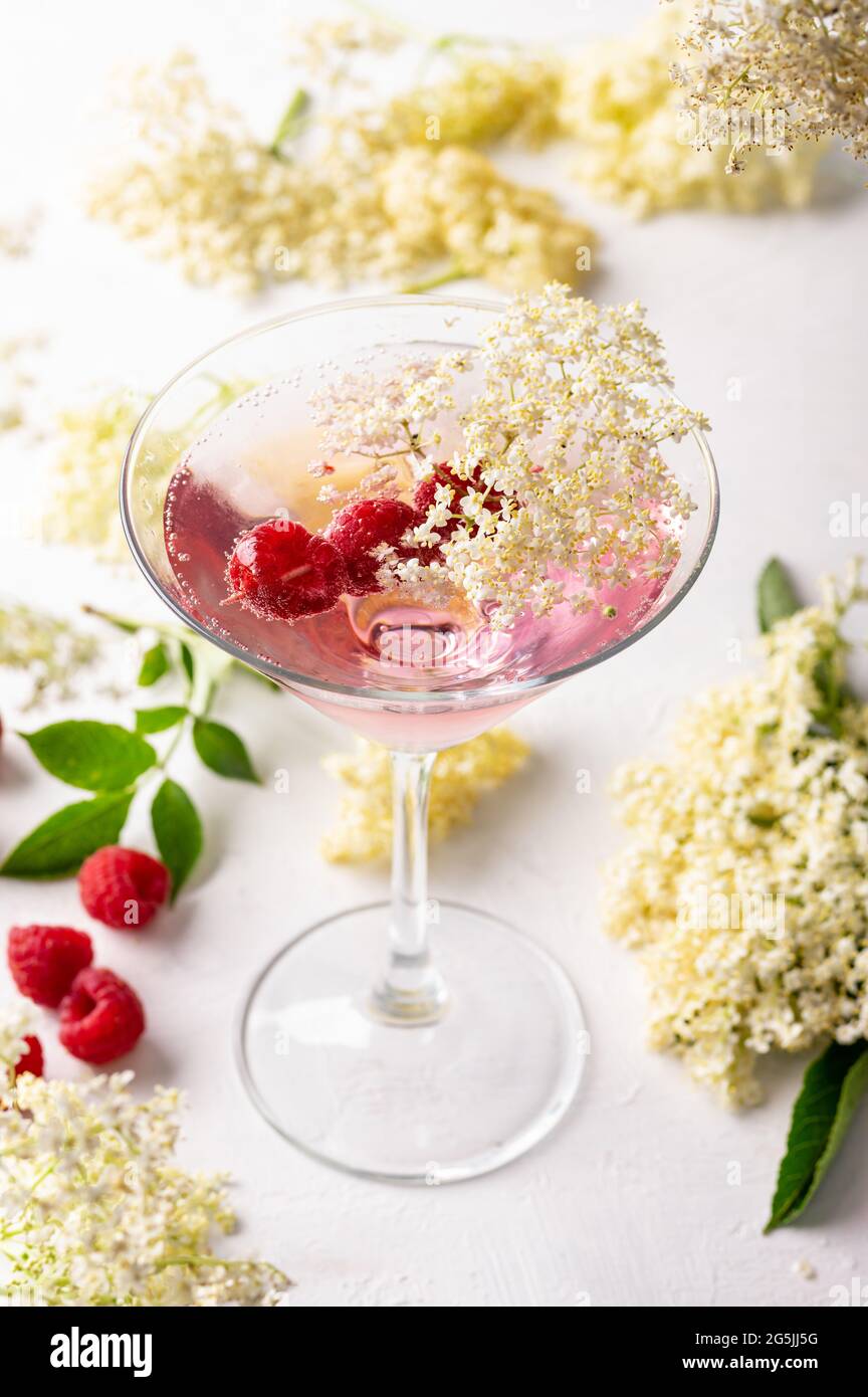 Gin und Tonic mit Holunderblüten erfrischenden Sommer rosa Cocktail garniert mit Himbeeren Stockfoto