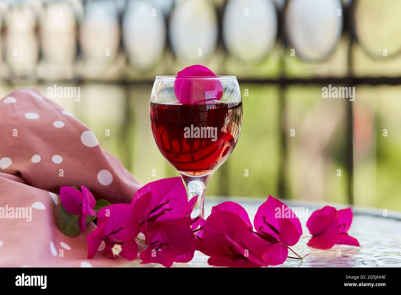 Elegantes Glas Rotwein. Dekorative rosa Blüten von Bougainvillea in einem Glas. Romantisches Konzept. Speicherplatz kopieren. Stockfoto