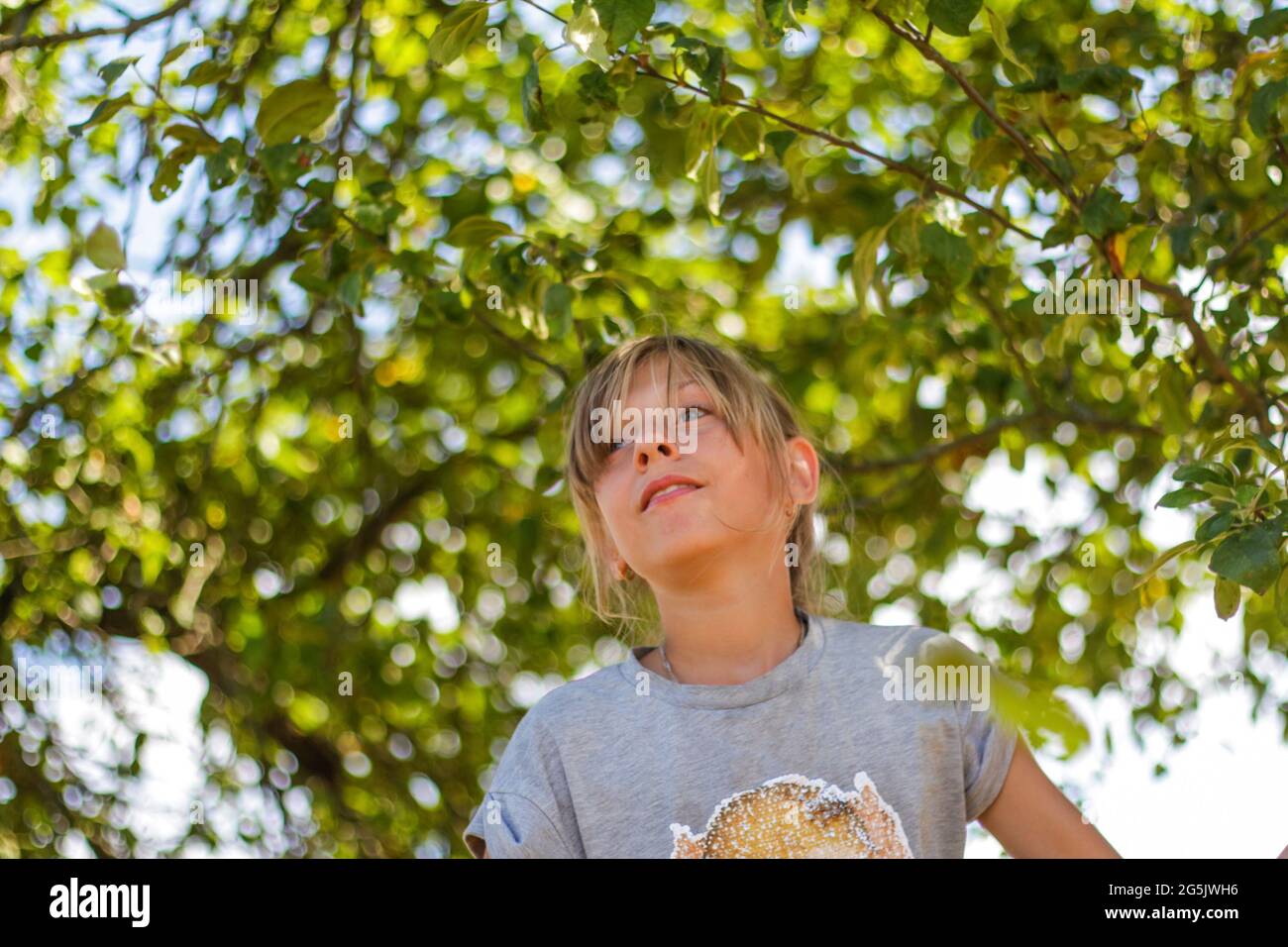 Defocused präteen blonde Mädchen auf grünen Baum Sommer Hintergrund. Kostenlose glückliche Kindheit. Liebe die Natur. Nicht fokussiert Stockfoto
