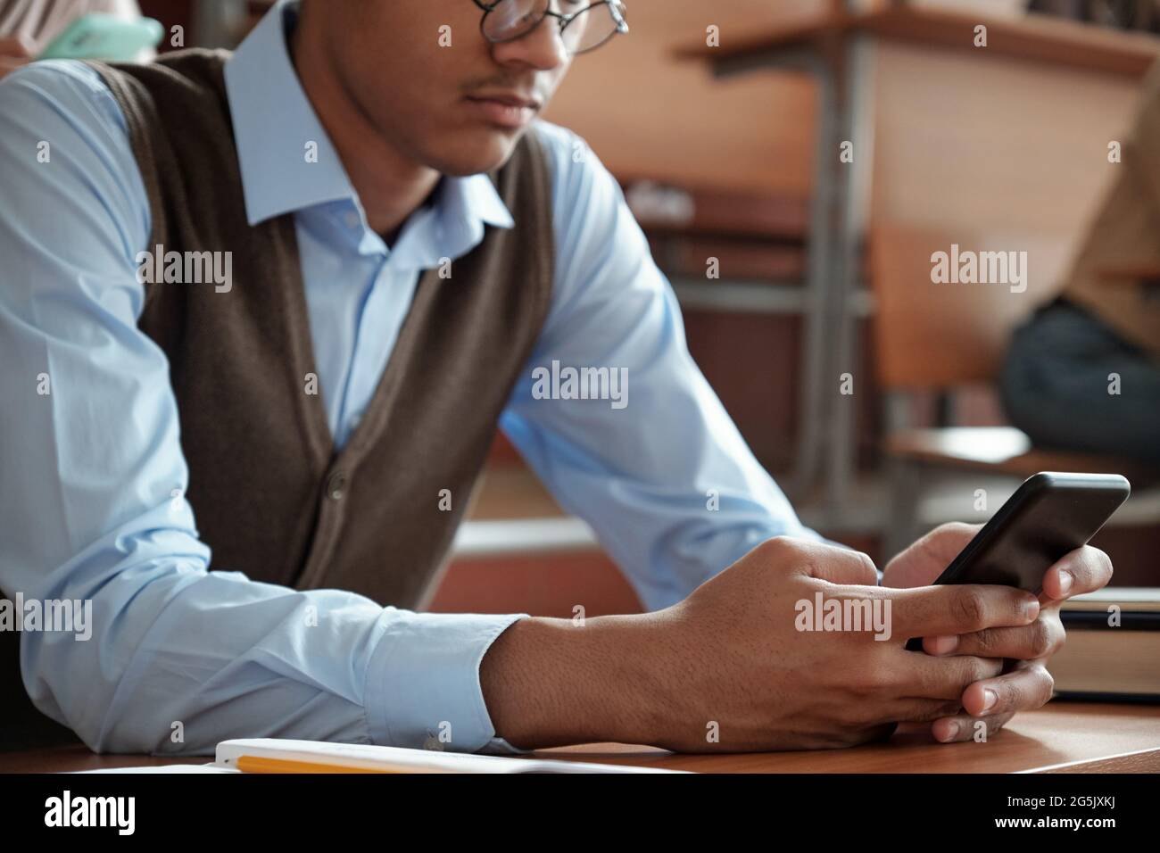 Hände eines Mixed-Race-Typen mit Smartphone am Schreibtisch Stockfoto