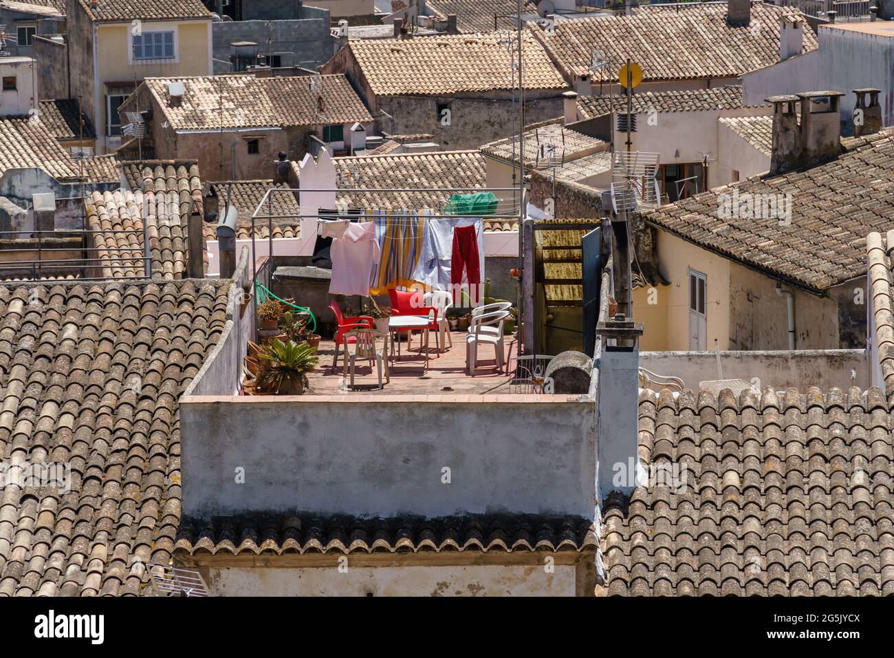 Trocknen von Kleidung auf einer Wäscheleine im Freien. Häuser mit traditionellen Dachziegeln in der schönen Altstadt von Arta, Mallorca, Spanien. Mediterrane Kultur. Stockfoto