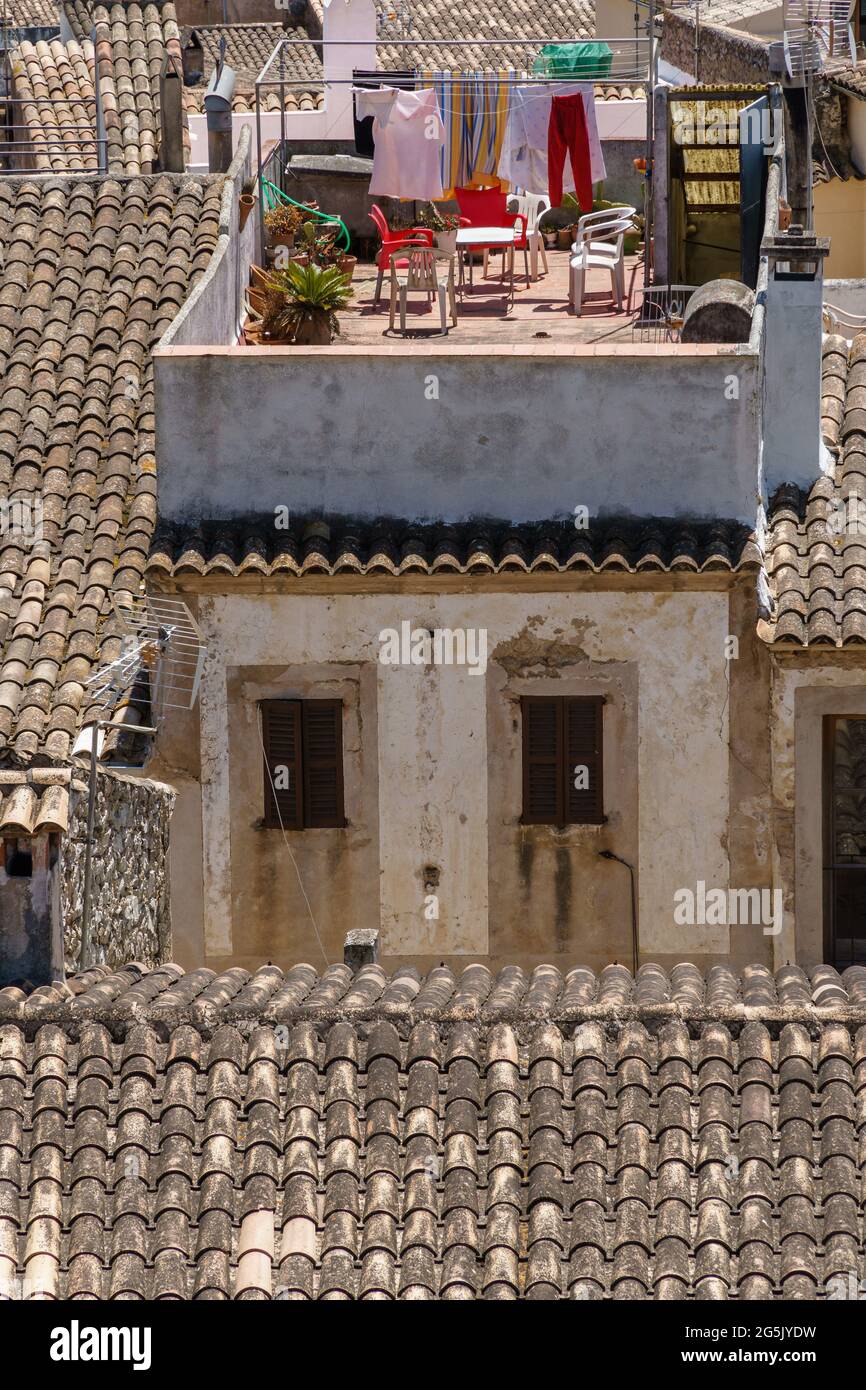 Trocknen von Kleidung auf einer Wäscheleine im Freien. Häuser mit traditionellen Dachziegeln in der schönen Altstadt von Arta, Mallorca, Spanien. Mediterrane Kultur. Stockfoto