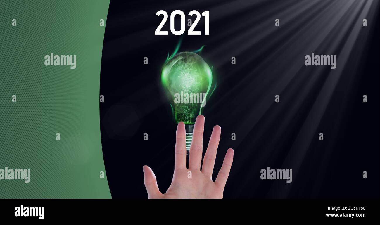 Komposition aus grünem Kopierraum über Jahr 2021, Hand und Leuchtmittel grün, auf schwarz Stockfoto