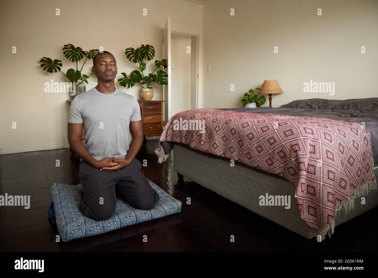 Junger afrikanischer Mann meditiert auf dem Boden seines Schlafzimmers Stockfoto