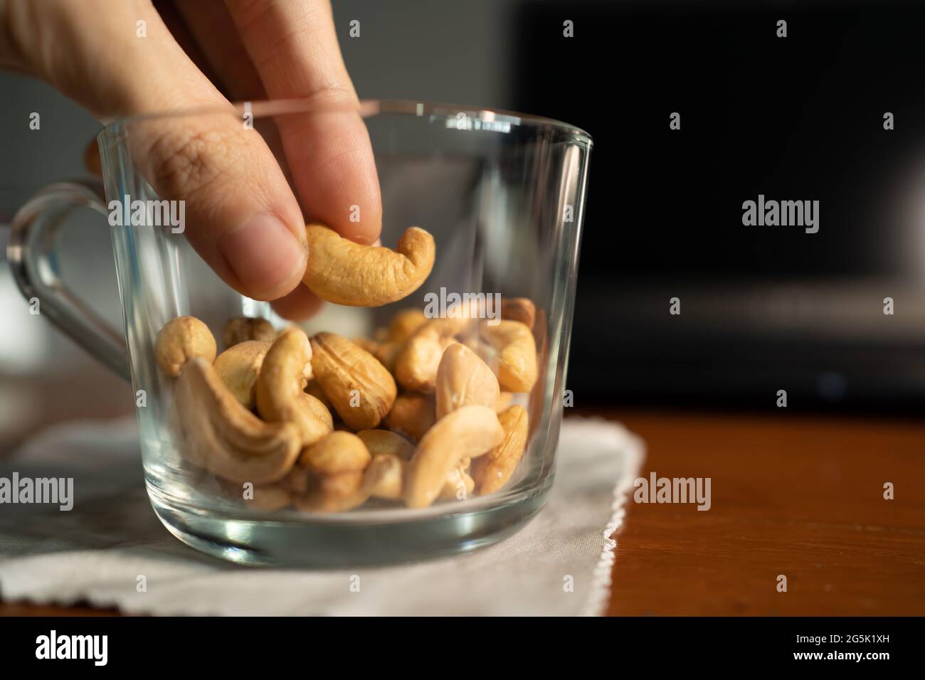 Pflücken gerösteter Cashewnuss aus einer Tasse Stockfoto