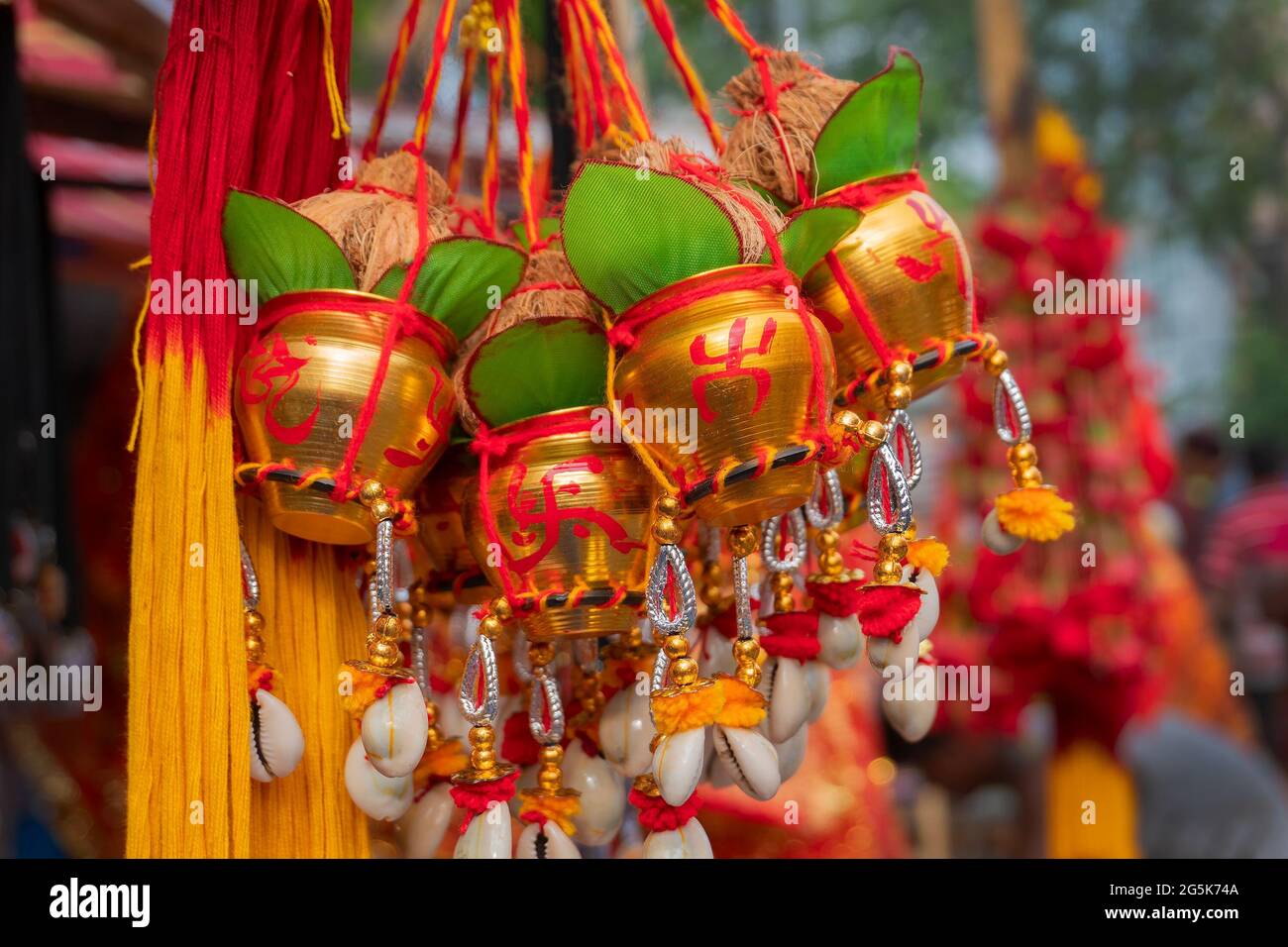 Kleine goldene Kupfereimer mit auspicions hinduistisch roten Symbolen auf ihnen, Blätter, Kokosnüsse mit anhängenden Verehrungsfäden, werden in Kalighat, Kol, verkauft Stockfoto