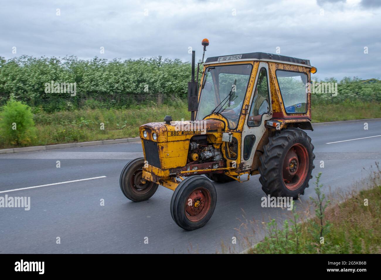 27. Juni 2021 - Pocklington, East Yorkshire, UK - Beacon Young Farmers Club Tractor Run. Alter und rostiger gelber Traktor auf der Straße. Stockfoto