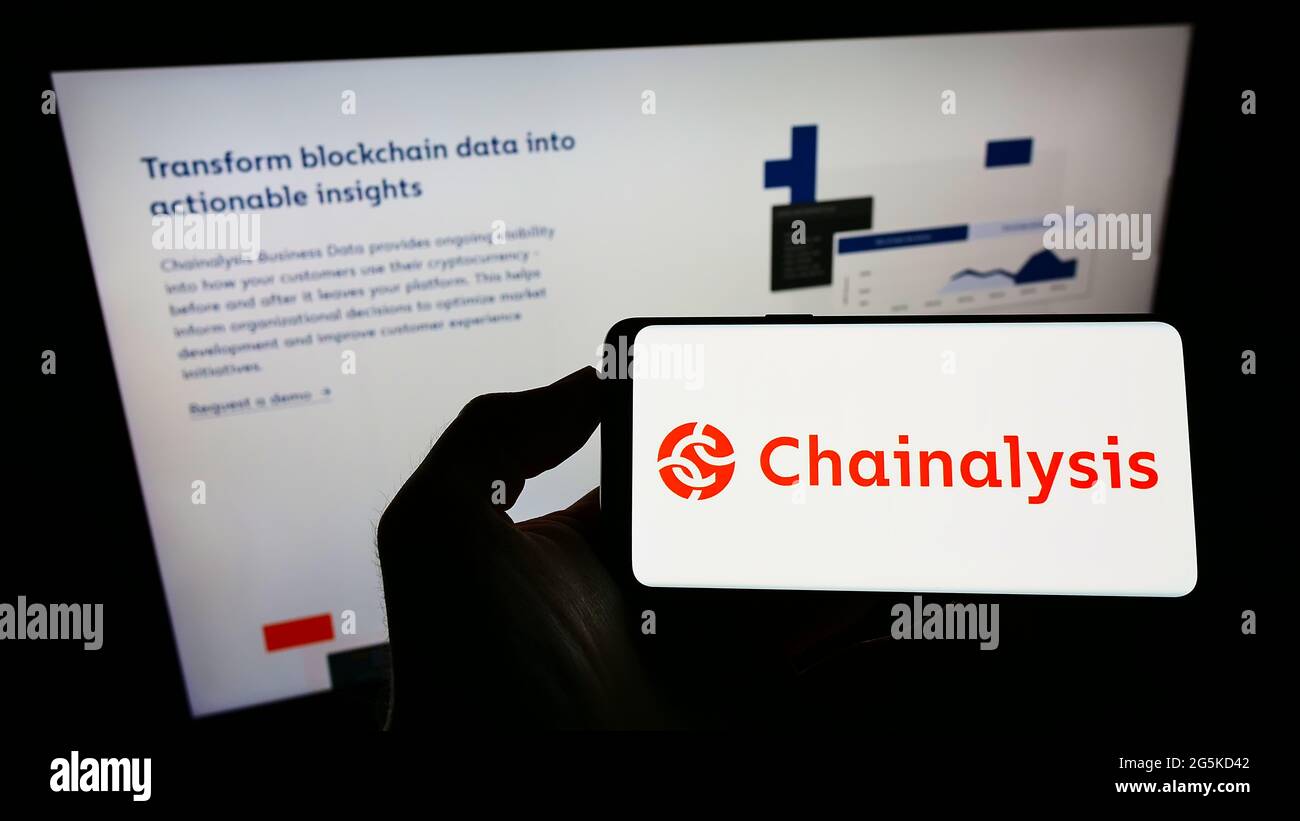 Person, die Mobiltelefon mit dem Logo des US-Kryptowährungsunternehmens Chainalysis Inc. Auf dem Bildschirm vor der Unternehmenswebseite hält. Konzentrieren Sie sich auf die Telefonanzeige. Stockfoto