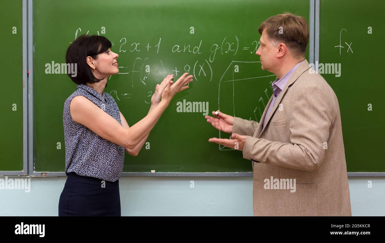 Ein Schüler erklärt dem Lehrer die Lösung des Problems an der Tafel. Stockfoto