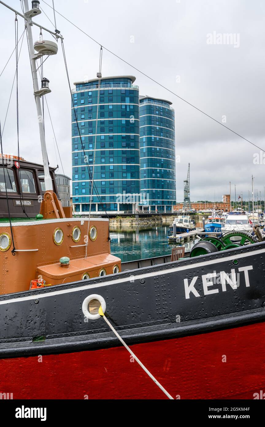 Die Quays Wohntürme mit dem Schlepper MT Kent, der im Vordergrund an der Chatham Maritime Marina, Kent, England, festgemacht ist. Stockfoto