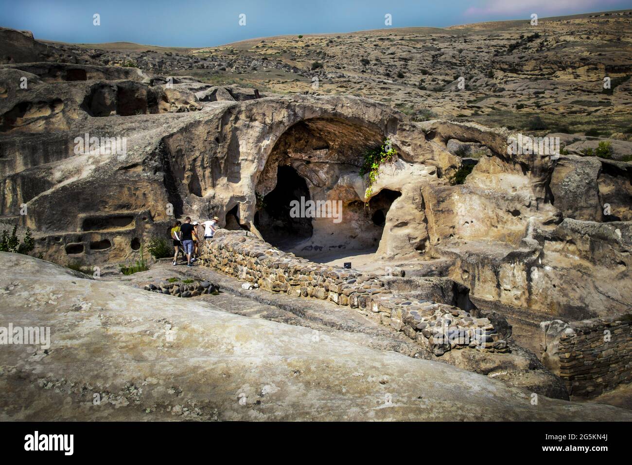 Zwei junge Paare machen sich auf den Weg nach unten, um einen zu erkunden Tiefdunkle Höhle in der prähistorischen Höhlenstadt Uplistsikhe in der Nähe von Gori Georgien Stockfoto