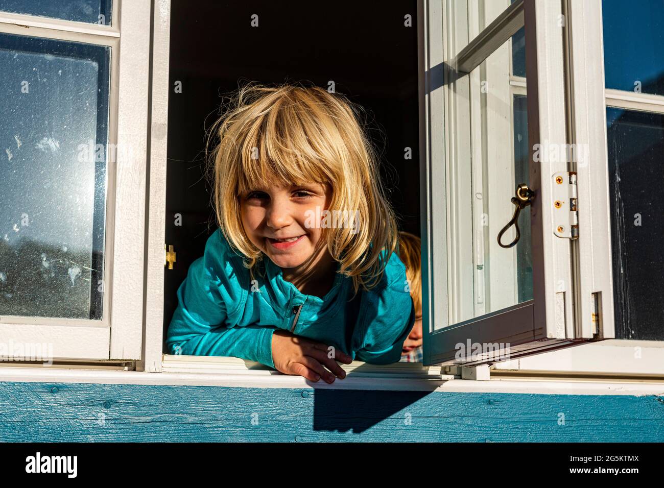 Mädchen, das durch ein Fenster schaut, Dorf A, Lofoten, Norwegen, Europa Stockfoto
