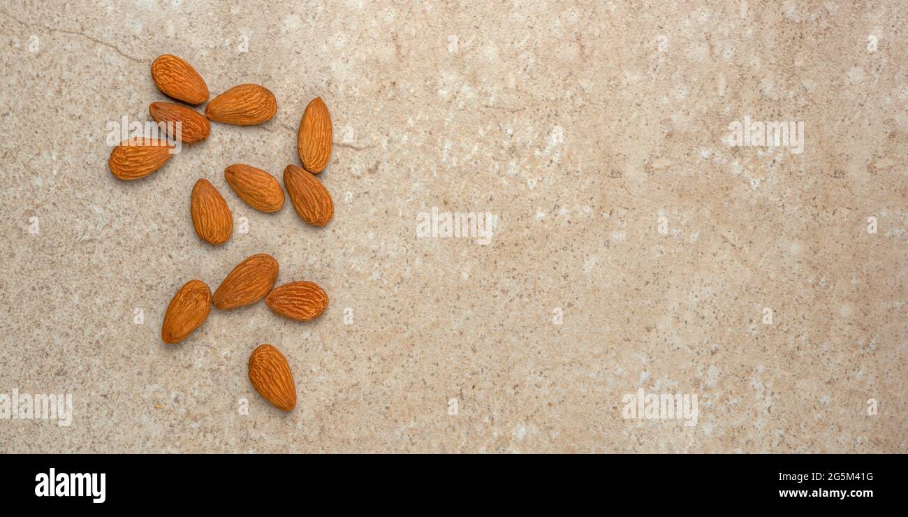 Geschälte Mandeln. Nusshintergrund, Banner, Mandeln in der Draufsicht in einer Untertasse und verstreut. Platzieren, um Text oder Design einzufügen. Stockfoto