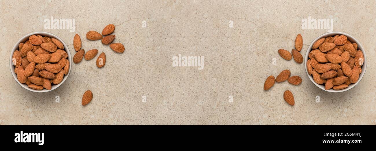 Geschälte Mandeln. Nusshintergrund, Banner, Mandeln in der Draufsicht in einer Untertasse und verstreut. Platzieren, um Text oder Design einzufügen. Stockfoto