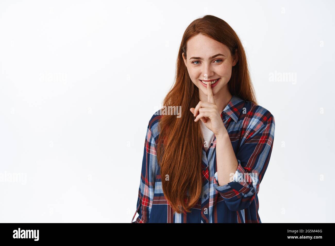 Bild von hübschen kaukasischen Mädchen mit roten Haaren lächelt, zu schüchtern, drücken Sie Finger auf die Lippen, ruhig oder tabu Geste, mit geheimnisvollen Gesicht, stehend zu schweigen Stockfoto