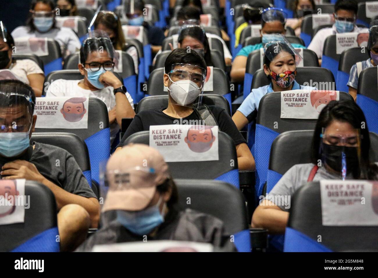 Patienten mit Schutzmasken als Vorsichtsmaßnahme gegen die Ausbreitung des Coronavirus beobachten eine physische Distanzierung, während sie sich anstellen, um eine Dosis des Sinovac COVID-19-Impfstoffes in einem Kino zu erhalten, das zu einer temporären Impfstelle in Manila, Philippinen, wurde. Stockfoto